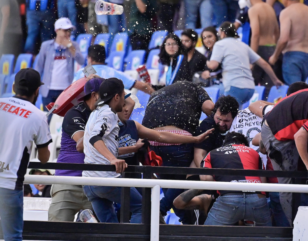 Aficionados de Gallos Blancos y de Atlas enfrentándose.