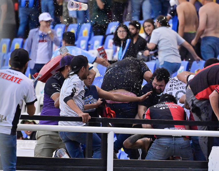 Aficionados de Gallos Blancos y de Atlas enfrentándose.