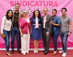 Fotografía grupal frente a un fondo rosa con el texto 'Sindicatura Fuerte y de Corazón'. Al centro, Catalina Verónica Atenco Pérez (Verónica Atenco Pérez), síndica municipal de Cuernavaca, viste un vestido azul con detalles blancos y un pañuelo rosa al cuello, rodeada por el diputado federal Adrián Martínez Terrazas, colaboradores y miembros de su equipo.